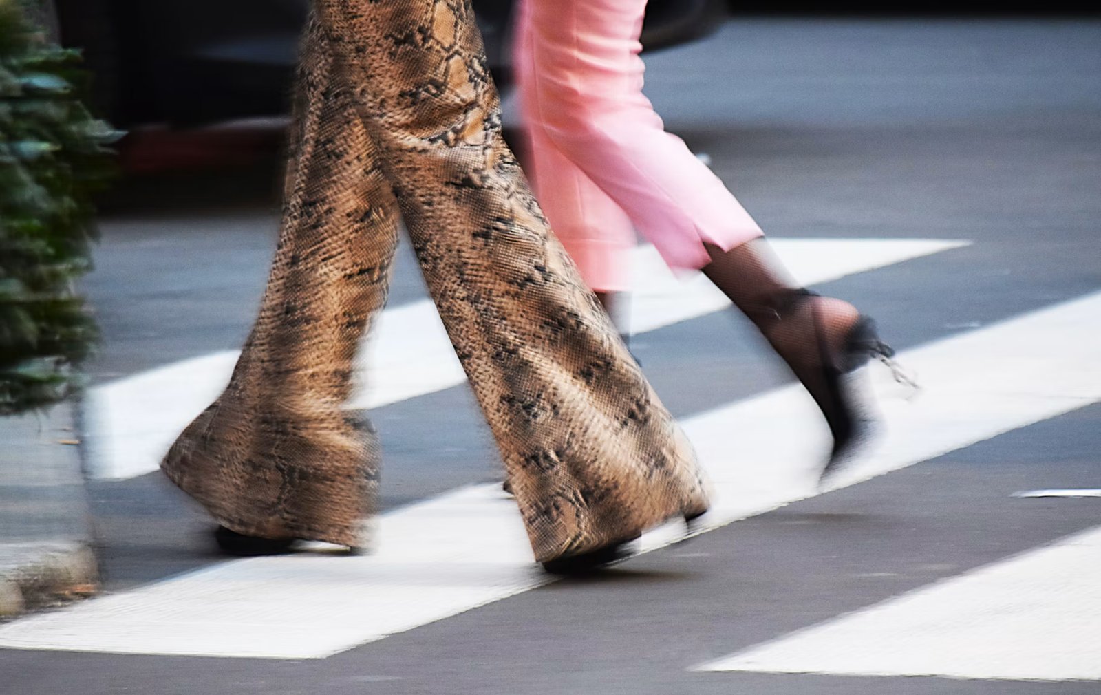 Printed flared trousers and pink trousers in motion on a city street